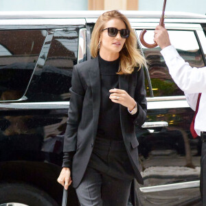 Rosie Huntington-Whiteley ultrachic à New York en tailleur pantalon et pull noirs. Une tenue accessoirisée de lunettes de soleil Saint Laurent, d'un sac CÉLINE et de sandales Gianvito Rossi. Le 28 avril 2016.