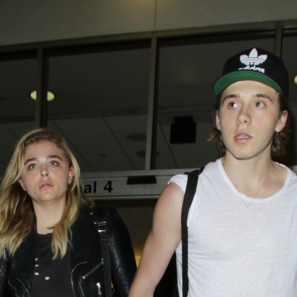 Chloë Grace Moretz et son compagnon Brooklyn Beckham arrivent à l'aéroport de LAX main dans la main à Los Angeles, Californie, le 30 juin 2016.