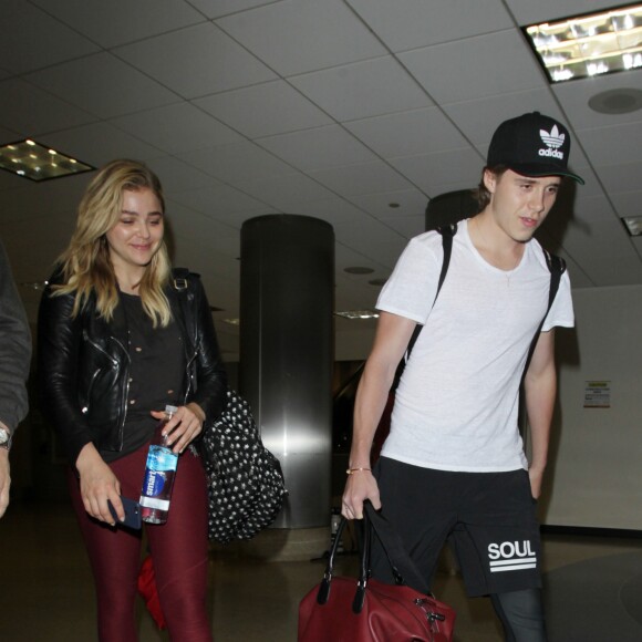 Chloë Grace Moretz et son compagnon Brooklyn Beckham arrivent à l'aéroport de LAX main dans la main à Los Angeles, Californie, le 30 juin 2016.
