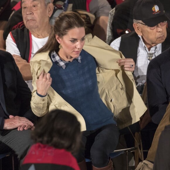 La duchesse Catherine enlève son trench Holland and Holland lors de la cérémonie. Kate Middleton et le prince William, duchesse et duc de Cambridge, ont pris part à une cérémonie de bienvenue traditionnelle lors de leur rencontre avec la nation Heiltsuk à la réserve amérindienne de Bella Bella le 26 septembre 2016, au troisième jour de leur visite officielle au Canada.