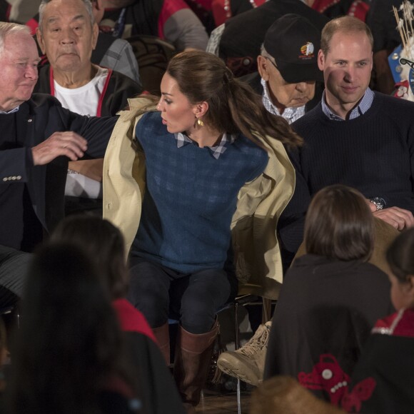 La duchesse Catherine enlève son trench Holland and Holland lors de la cérémonie. Kate Middleton et le prince William, duchesse et duc de Cambridge, ont pris part à une cérémonie de bienvenue traditionnelle lors de leur rencontre avec la nation Heiltsuk à la réserve amérindienne de Bella Bella le 26 septembre 2016, au troisième jour de leur visite officielle au Canada.