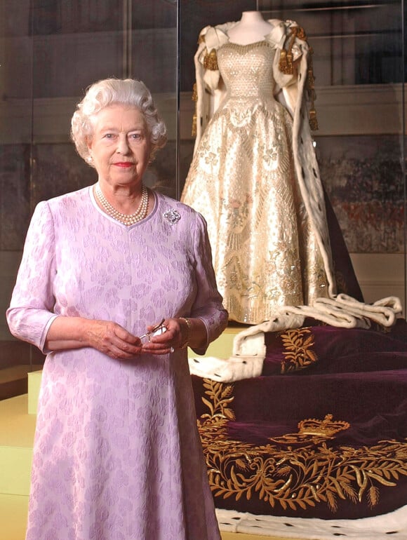 La reine Elisabeth II pose devant la robe de son courronement dans le cadre d'une exposition d'été à Buckingham Palace, le 1er août 2003.