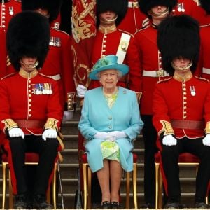 La reine Elizabeth II posant avec les gardes dans les jardins du palais de Buckingham à Londres en juin 2013.