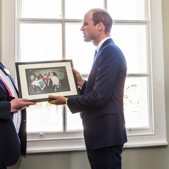 Le prince William, duc de Cambridge, en visite le 13 mai 2016 dans les locaux de l'organisation "The Passage", qui aide les sans-abris à retrouver une vie meilleure, à Londres. A l'occasion de sa visite, il a reçu en cadeau une photo de sa mère Diana et de son frère Harry prise en 1994 dans ce même endroit.