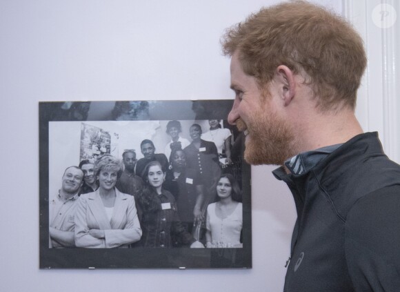 Le prince Harry en visite dans un foyer auprès de l'association The Running Charity qui aide les jeunes sans-abri, le 26 janvier 2017 à Londres. Sa mère Lady Diana avait inauguré le foyer dans les années 1990, comme une photo d'époque en témoigne.
