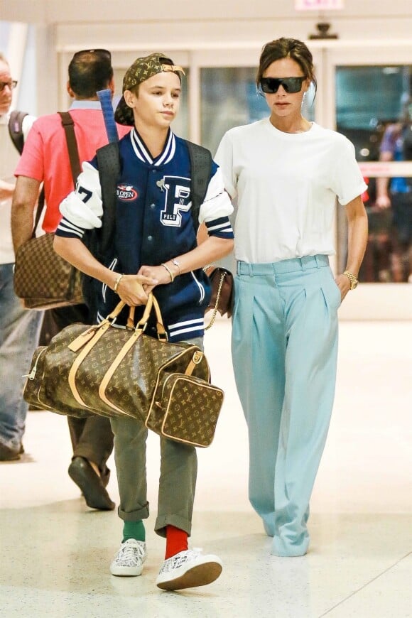 Victoria Beckham et son fils Romeo (habillé d'une casquette Louis Vuitton x Supreme, d'une veste Polo Ralph Lauren, chaussé de baskets Comme des Garçons et tenant un sac Louis Vuitton) à l'aéroport de JFK à New York. Le 30 août 2017.