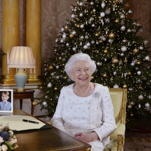 La reine Elizabeth II dans le salon 1844 au palais de Buckingham pour l'enregistrement de son allocution de Noël, le 25 décembre 2017. Sur le bureau à côté d'elle, des photos de George et Charlotte de Cambridge, de son mariage avec le prince Philip et de leurs noces de platine. Mais dans la pièce figurait aussi une photo des fiançailles du prince Harry et de Meghan Markle, qui s'apprête à entrer dans la famille.