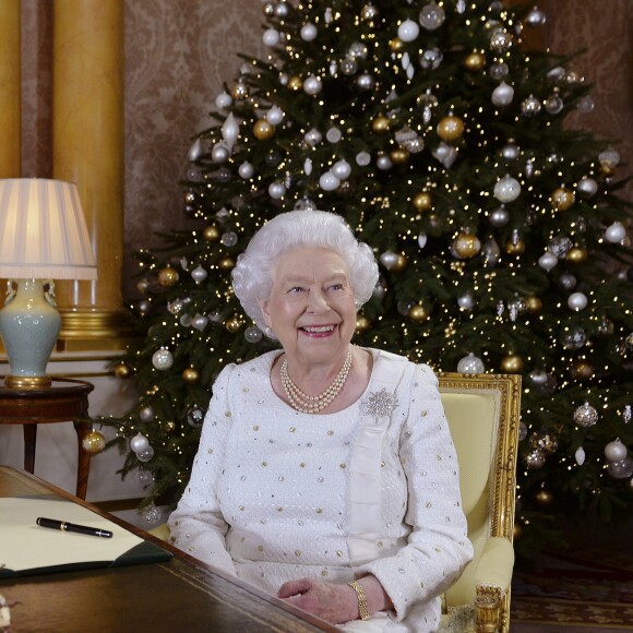 La reine Elizabeth II dans le salon 1844 au palais de Buckingham pour l'enregistrement de son allocution de Noël, le 25 décembre 2017. Sur le bureau à côté d'elle, des photos de George et Charlotte de Cambridge, de son mariage avec le prince Philip et de leurs noces de platine. Mais dans la pièce figurait aussi une photo des fiançailles du prince Harry et de Meghan Markle, qui s'apprête à entrer dans la famille.