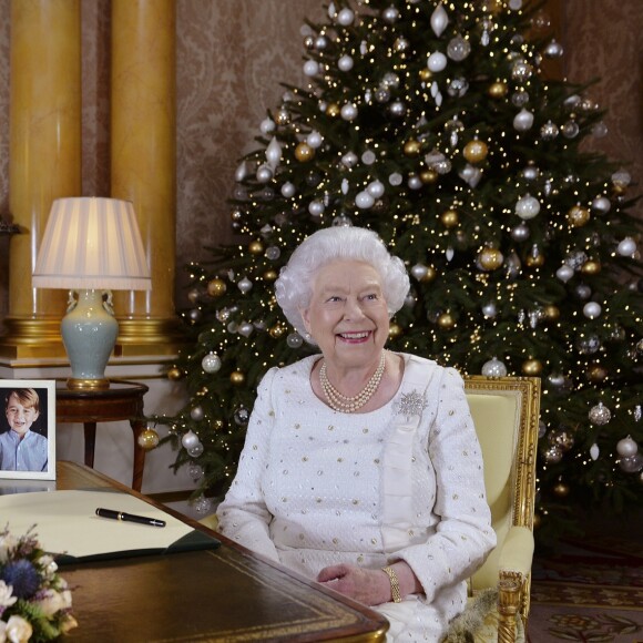 La reine Elizabeth II dans le salon 1844 au palais de Buckingham pour l'enregistrement de son allocution de Noël, le 25 décembre 2017. Sur le bureau à côté d'elle, des photos de George et Charlotte de Cambridge, de son mariage avec le prince Philip et de leurs noces de platine. Mais dans la pièce figurait aussi une photo des fiançailles du prince Harry et de Meghan Markle, qui s'apprête à entrer dans la famille.