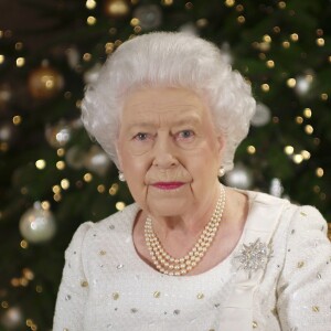 La reine Elizabeth II dans le salon 1844 au palais de Buckingham pour l'enregistrement de son allocution de Noël, le 25 décembre 2017. Sur le bureau à côté d'elle, des photos de George et Charlotte de Cambridge, de son mariage avec le prince Philip et de leurs noces de platine. Mais dans la pièce figurait aussi une photo des fiançailles du prince Harry et de Meghan Markle, qui s'apprête à entrer dans la famille.