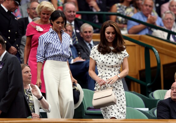 Meghan Markle en Ralph Lauren dans la royal box à Wimbledon le 14 juillet 2018 avec Kate Middleton. L'Américaine en a surpris plus d'un en pantalon large et chemise légèrement oversize, un ensemble pointu qui contraste avec le style plus classique de sa belle-soeur.
