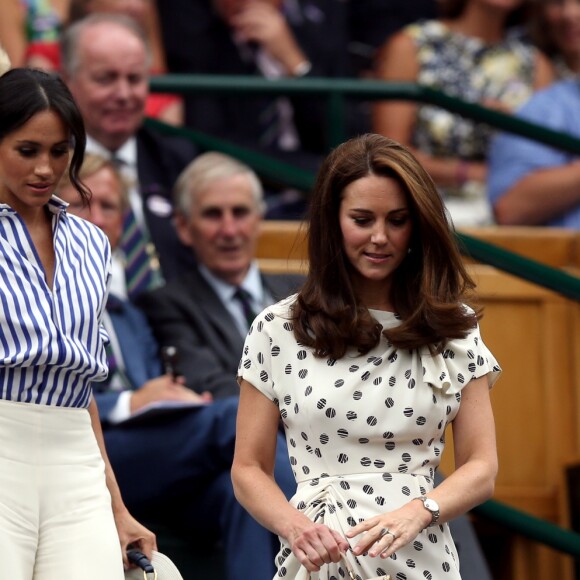 Meghan Markle en Ralph Lauren dans la royal box à Wimbledon le 14 juillet 2018 avec Kate Middleton. L'Américaine en a surpris plus d'un en pantalon large et chemise légèrement oversize, un ensemble pointu qui contraste avec le style plus classique de sa belle-soeur.