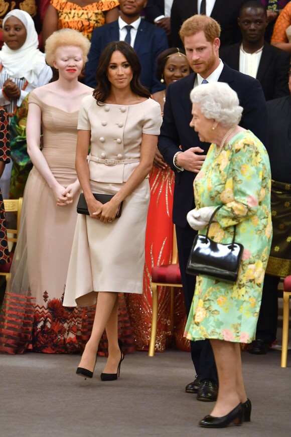 Meghan Markle en Prada avec la reine Elizabeth II et le prince Harry à la cérémonie "Queen's Young Leaders Awards" au palais de Buckingham, à Londres, le 26 juin 2018. Un ensemble à double boutonnage plutôt classique, qui n'est pas sans rappeler le style de Jackie Kennedy.