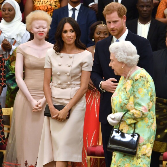 Meghan Markle en Prada avec la reine Elizabeth II et le prince Harry à la cérémonie "Queen's Young Leaders Awards" au palais de Buckingham, à Londres, le 26 juin 2018. Un ensemble à double boutonnage plutôt classique, qui n'est pas sans rappeler le style de Jackie Kennedy.