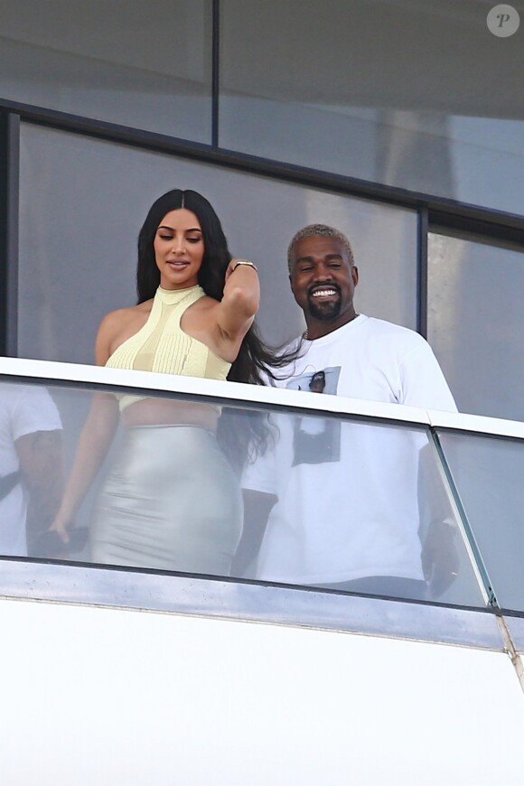 Kanye West et sa femme Kim Kardashian saluent la foule sur le balcon de leur nouvel appartement à Miami, le 4 janvier 2019.