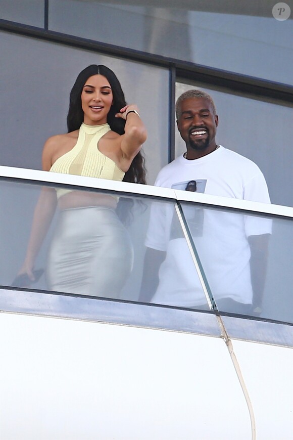 Kanye West et sa femme Kim Kardashian saluent la foule sur le balcon de leur nouvel appartement à Miami, le 4 janvier 2019.