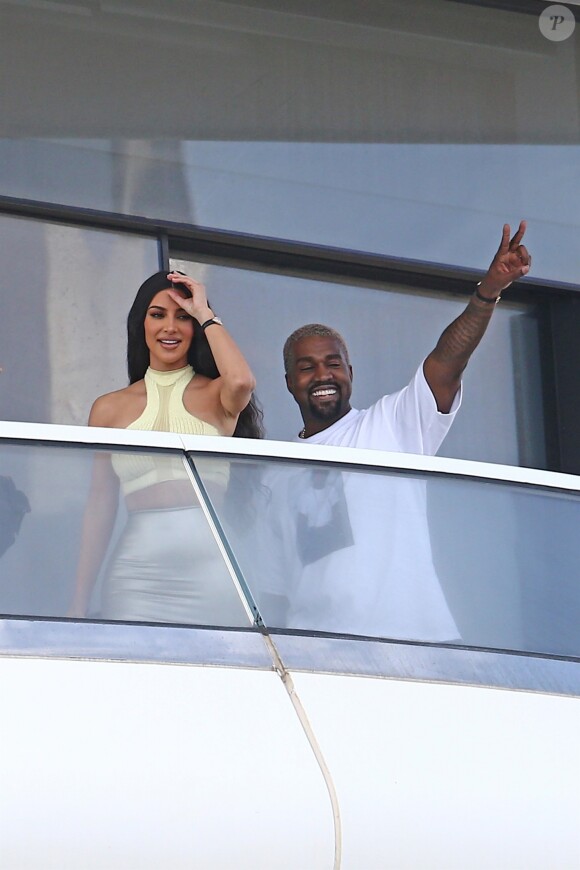 Kanye West et sa femme Kim Kardashian saluent la foule sur le balcon de leur nouvel appartement à Miami, le 4 janvier 2019.
