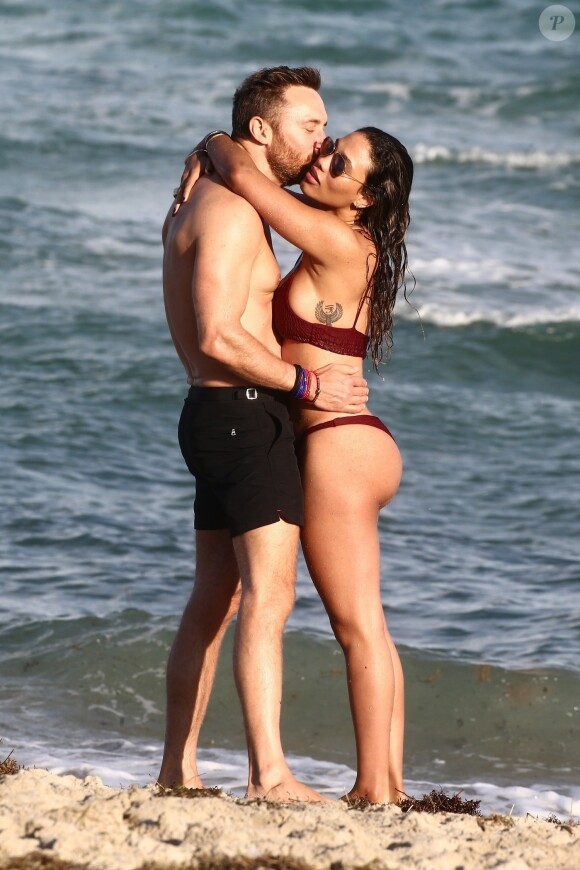 David Guetta et sa compagne Jessica Ledon, qui arbore un diamant à l'annulaire gauche, passent du bon temps sur la plage en compagnie de leur petit chien. Miami, le 23 novembre 2018.