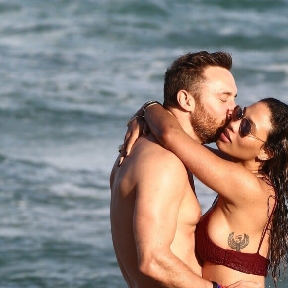 David Guetta et sa compagne Jessica Ledon, qui arbore un diamant à l'annulaire gauche, passent du bon temps sur la plage en compagnie de leur petit chien. Miami, le 23 novembre 2018.