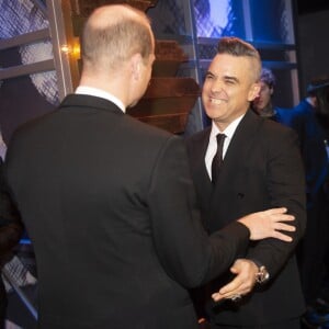 Le prince William salue le chanteur Robbie Williams le 18 novembre 2019 au Palladium Theatre à Londres lors de la Royal Variety Performance, gala annuel au profit de la Royal Variety Charity qui soutient les professionnels du divertissement dans le besoin.