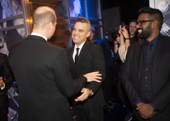 Le prince William salue le chanteur Robbie Williams le 18 novembre 2019 au Palladium Theatre à Londres lors de la Royal Variety Performance, gala annuel au profit de la Royal Variety Charity qui soutient les professionnels du divertissement dans le besoin.