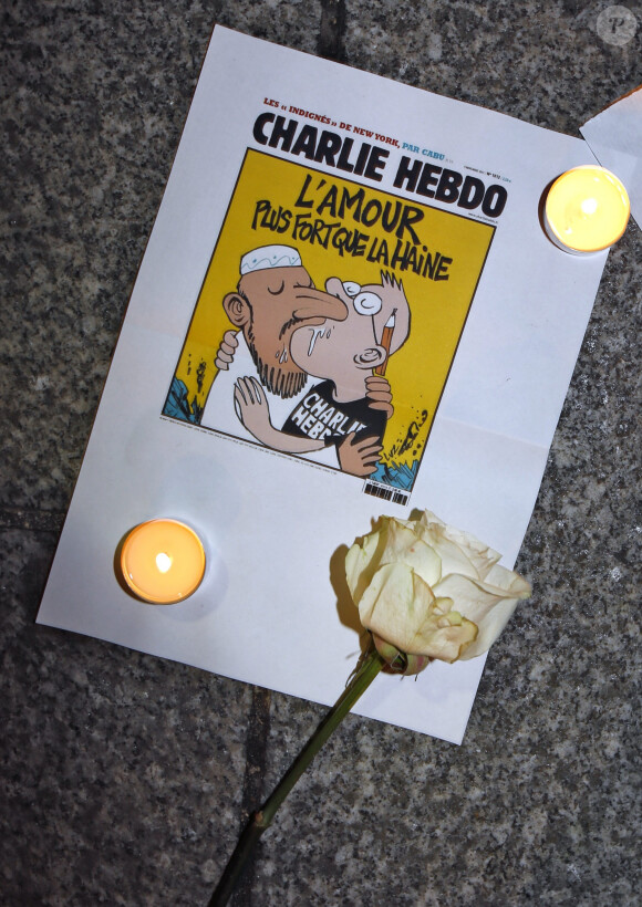 Fleur, bougies et Une de "Charlie Hebdo" déposées devant le siège de "Charlie Hebdo" à Paris, le 7 janvier 2015.
