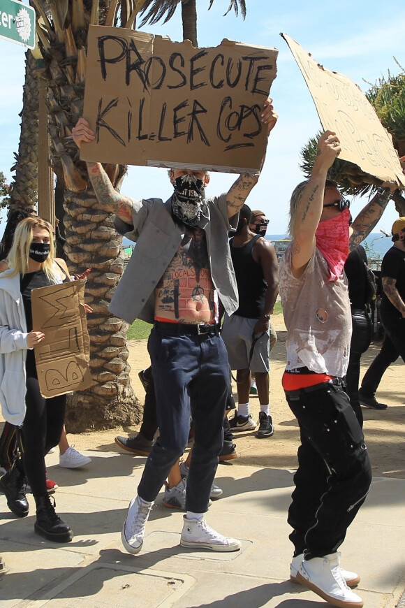 Machine Gun Kelly proteste contre les violences policières, suite à la mort de George Floyd, avec un carton affichant le message "Poursuivez les policiers tueurs". Los Angeles, le 31 mai 2020.
