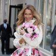 Celine Dion rayonnante et très souriante dans un ensemble pull écru et jupe bouffante fleurie salue ses fans à la sortie de son hôtel à New York, le 8 mars 2020   