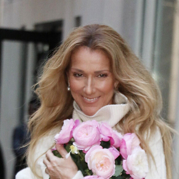 Celine Dion rayonnante et très souriante dans un ensemble pull écru et jupe bouffante fleurie salue ses fans à la sortie de son hôtel à New York, le 8 mars 2020.