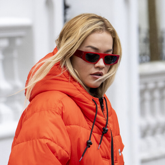 La chanteuse britannique Rita Ora quitte son appartement londonien, vêtue d'une doudoune orange et d'un pantalon de type camouflage, le 12 octobre 2020.