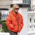 La chanteuse britannique Rita Ora quitte son appartement londonien, vêtue d'une doudoune orange et d'un pantalon de type camouflage, le 12 octobre 2020.