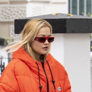 La chanteuse britannique Rita Ora quitte son appartement londonien, vêtue d'une doudoune orange et d'un pantalon de type camouflage, le 12 octobre 2020.