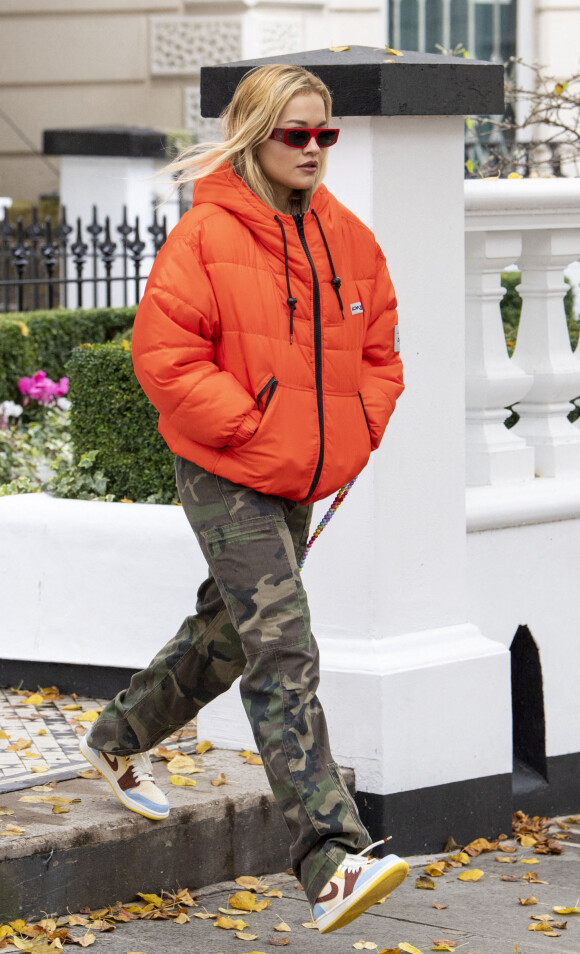 La chanteuse britannique Rita Ora quitte son appartement londonien, vêtue d'une doudoune orange et d'un pantalon de type camouflage, le 12 octobre 2020.