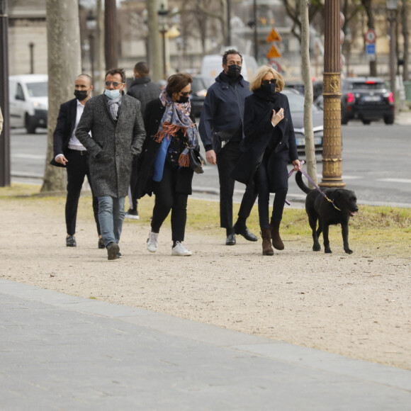 La première dame Brigitte Macron balade son chien, Némo, sur l'avenue des Champs-Élysées, à Paris, France, le 26 mars 2021. La première dame est accompagnée de Bernard Montiel et une amie ainsi que de ses gardes du corps. Elle s'est rendue à l'exposition des 20 statues du "Chat" de Philippe Geluck. © Christophe Clovis/Bestimage