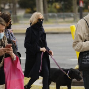 La première dame Brigitte Macron balade son chien, Némo, sur l'avenue des Champs-Élysées, à Paris, France, le 26 mars 2021. La première dame est accompagnée de Bernard Montiel et une amie ainsi que de ses gardes du corps. Elle s'est rendue à l'exposition des 20 statues du "Chat" de Philippe Geluck. © Christophe Clovis/Bestimage