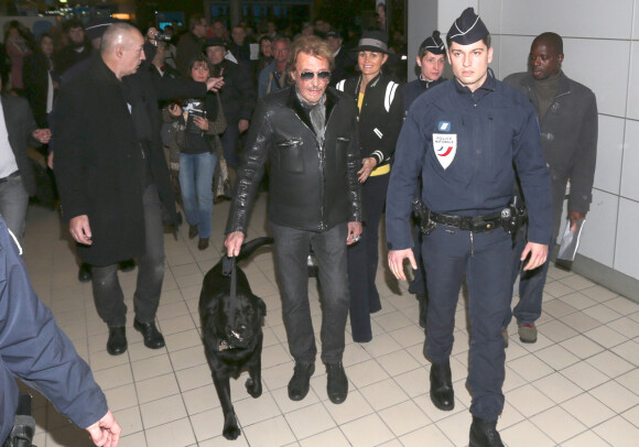 Johnny et Laeticia Hallyday arrivent à Paris avec leur chien Santos. Le 8 décembre 2013.