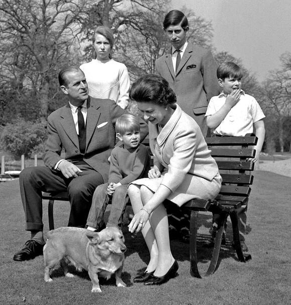 La reine Elizabeth II et l'un de ses corgis lors d'une séance photo en famille à Frogmore House en 1968, avec le duc d'Edimbourg, la princesse Anne, le prince Charles, le prince Edward (sur le banc) et le prince Andrew.