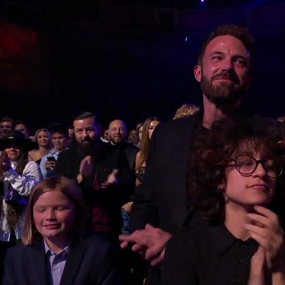 Jennifer Lopez reçoit un Icon Award sur la scène des "iHeartRadio Music Awards", sous le regard de son compagnon Ben Affleck et de sa fille Emme. Los Angeles, le 22 mars 2022. 