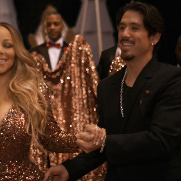 Images de la vidéo spéciale Noël de Mariah Carey. Elle porte une robe Dolce and Gabbana à perles dorées aux dires de la chanteuse "pesait entre 60 et 70 livres".