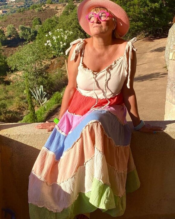 Christine Bravo pose en robe décolletée, chez elle en Corse. Instagram, août 2022.
