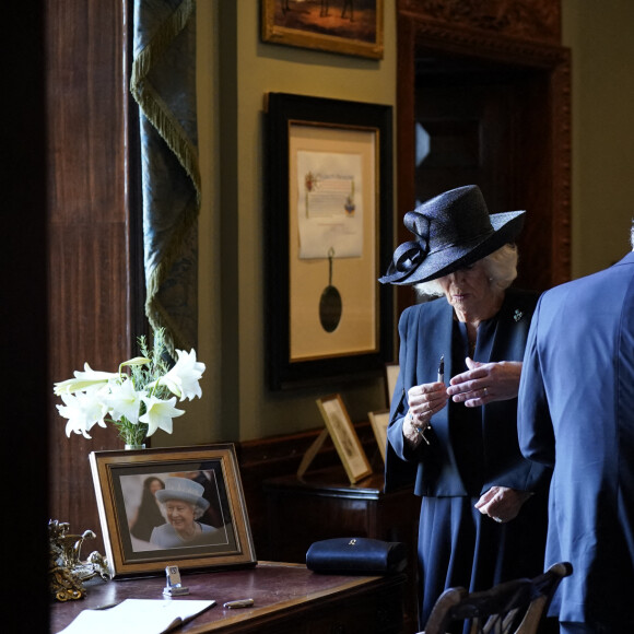 Camilla Parker Bowles, reine consort d'Angleterre, examine le stylo défectueux avec lequel le roi Charles III a signé le livre d'or au Hillsborough Castle le 13 septembre 2022.