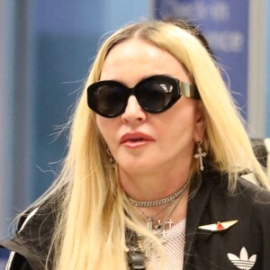 Madonna et son fils David Banda, 16 ans, arrivent à l'aéroport JFK à New York, le 11 août 2022. Au moment de passer le contrôle avant d'embarquer, la chanteuse de 63 ans laisse apparaître son tee-shirt en résille transparent.