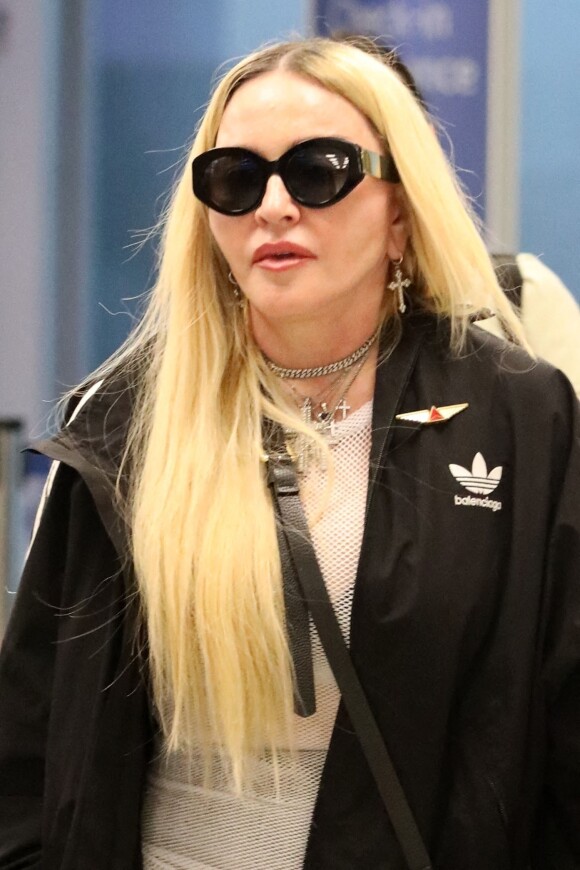 Madonna et son fils David Banda, 16 ans, arrivent à l'aéroport JFK à New York, le 11 août 2022. Au moment de passer le contrôle avant d'embarquer, la chanteuse de 63 ans laisse apparaître son tee-shirt en résille transparent.