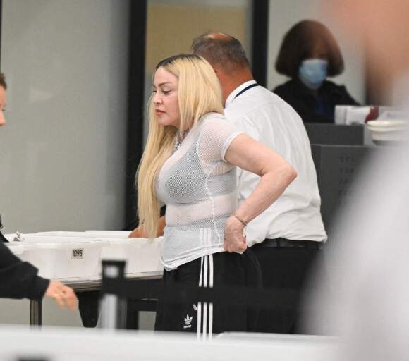 Madonna et son fils David Banda, 16 ans, arrivent à l'aéroport JFK à New York, le 11 août 2022. Au moment de passer le contrôle avant d'embarquer, la chanteuse de 63 ans laisse apparaître son tee-shirt en résille transparent.