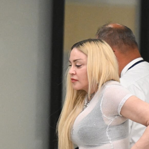 Madonna et son fils David Banda, 16 ans, arrivent à l'aéroport JFK à New York, le 11 août 2022. Au moment de passer le contrôle avant d'embarquer, la chanteuse de 63 ans laisse apparaître son tee-shirt en résille transparent.