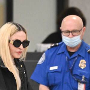 Madonna et son fils David Banda, 16 ans, arrivent à l'aéroport JFK à New York, le 11 août 2022. Au moment de passer le contrôle avant d'embarquer, la chanteuse de 63 ans laisse apparaître son tee-shirt en résille transparent.