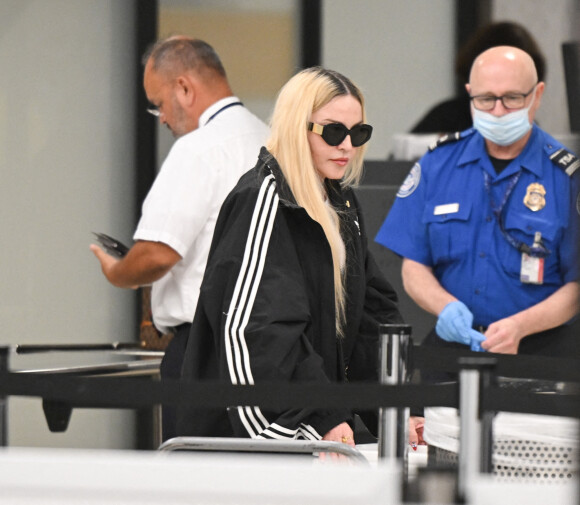 Madonna et son fils David Banda, 16 ans, arrivent à l'aéroport JFK à New York, le 11 août 2022. Au moment de passer le contrôle avant d'embarquer, la chanteuse de 63 ans laisse apparaître son tee-shirt en résille transparent.