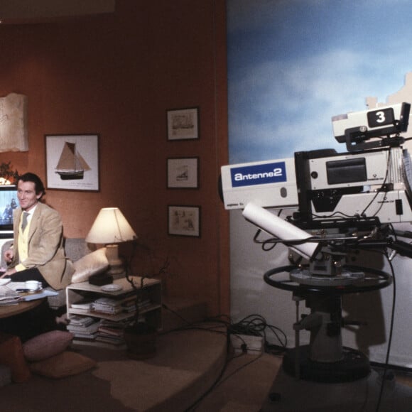 En France, à Paris, portrait de William Leymergie dans son bureau de l'avenue Montaigne où on enregistre "Télématin", le bureau est aménagé comme un appartement avec coin cuisine, canapé, table basse sur laquelle une tête mannequin supportant un casque, un récepteur de télévision, en compagnie Martine Allain-Regnault le 16 janvier 1985.