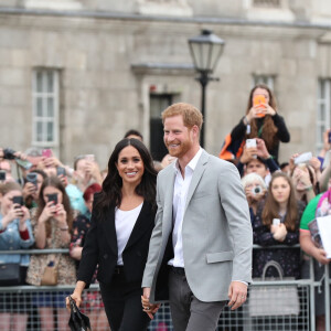 Le prince Harry, duc de Sussex et sa femme Meghan Markle, duchesse de Sussex saluent la foule lors de leur visite au collège de la trinité à Dublin le 11 juillet 2018 