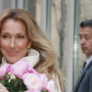 Celine Dion rayonnante et très souriante dans un ensemble pull écru et jupe bouffante fleurie salue ses fans à la sortie de son hôtel à New York, le 8 mars 2020